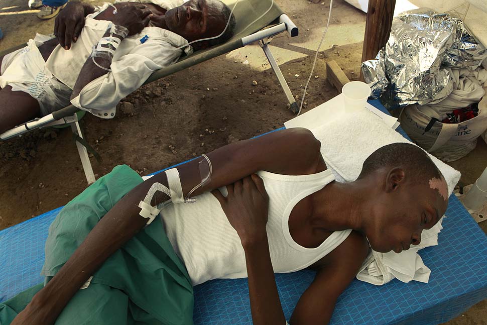 Two men suffering from cholera rest while receiving treatment at an emergency cholera clinic run by Samaritan's Purse outside of Cabaret, Haiti. Despite the work of aid organization, over 89,000 have been infected so far.